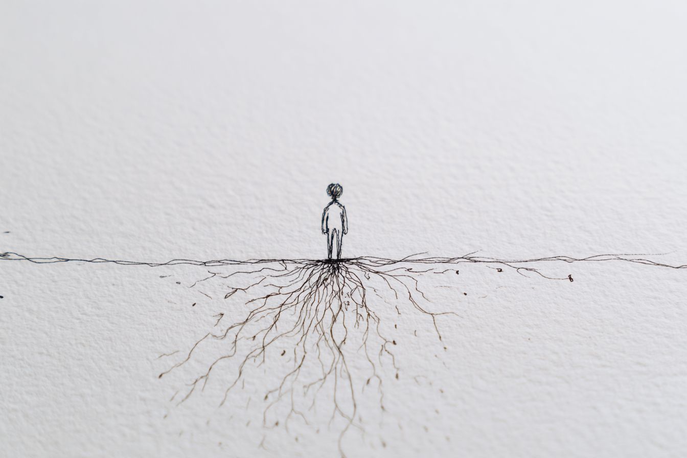 Eine simple Zeichnung zeigt eine kleine, stilisierte Figur, die auf einer Linie steht. Unter der Figur sind feine, verzweigte Wurzeln zu sehen, die sich ausbreiten und den Untergrund durchdringen. Der Hintergrund ist schlicht und unifarben, was die Figur und die Wurzeln hervorhebt.